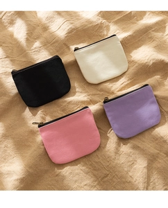 Flat lay of four minimalist canvas coin purses in black, beige, pink and purple colors