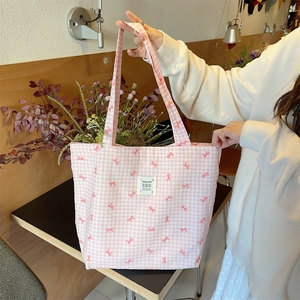 Pink and white checkered canvas tote bag with red bow prints and a white woven label
