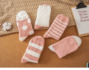 Detail showing five styles of pink coral fleece winter socks on a cozy knitted blanket