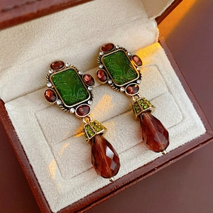 Detail of vintage gold earrings with green gems, red stones and brown crystal drops