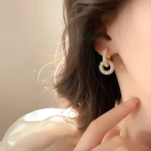 Close-up of elegant gold double-hoop earrings encrusted with sparkling white rhinestones