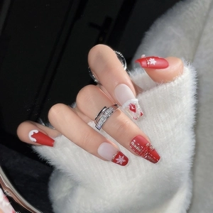 Christmas press-on nails with red and white snowflake art and 3D bow accents