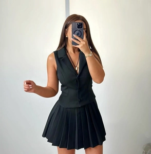 Selfie miroir montrant un ensemble gilet blazer sans manches noir et mini-jupe plissée