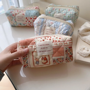 Close-up of quilted cotton cosmetic pouch with floral patterns and animal labels