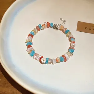 Colorful beaded bracelet with zircon and white flowers on a white ceramic plate