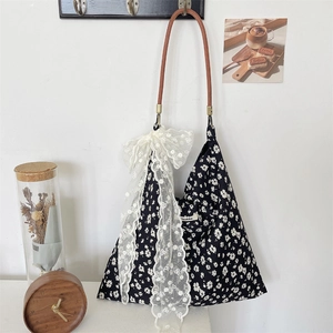 Détail du sac cabas en toile florale avec nœud en dentelle et bandoulière en cuir