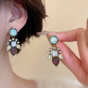 Close-up of vintage bronze earrings with light blue and lavender gemstones and rhinestones