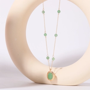 Dettaglio della collana vintage con pietra naturale verde e pendente dorato inciso su base