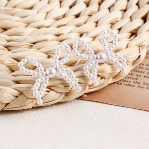 Detailed macro view of two handmade faux pearl bow hairclips on a vintage background
