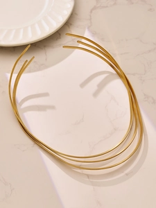 Ensemble de trois colliers rigides dorés minimalistes sur une surface en marbre élégant