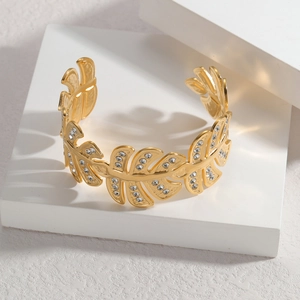 18K gold plated leaf cuff bracelet with sparkling zircon stones on a white stand