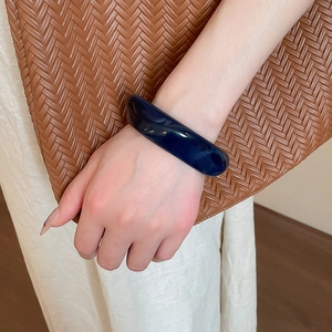 Close-up of deep blue marble resin cuff bracelet worn with stylish neutral outfit