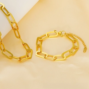 Detail of 18K gold paperclip link bracelet with K18 engraving on smooth champagne silk