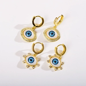 Detail of two pairs of gold evil eye earrings with sparkling crystal accents