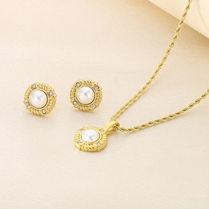 Detail of gold-plated twisted chain necklace and pearl stud earrings set with crystals
