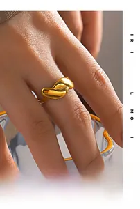 Detail of a minimalist gold wavy irregular ring on a hand with golden glass accents
