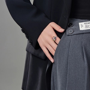 Close-up of hand wearing a rainbow zircon heart ring tucked into a suit pocket