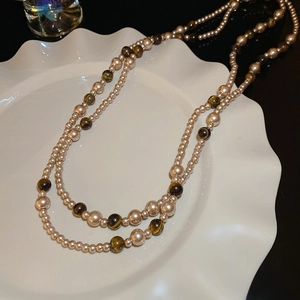 Dettaglio della collana di perle e occhio di tigre su vassoio bianco con sfondo scuro