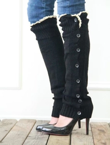Close-up of black knitted leg warmers with lace trim and grey button accents for women