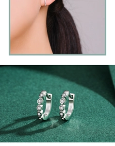 Detail of S925 sterling silver hoop earrings with zircon stones and polished finish