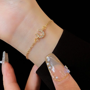 Bracelet fer à cheval doré avec zircons pavés porté au poignet pour un look luxe élégant