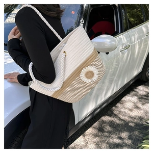 Fashionable floral woven straw tote bag with daisy detail worn by a model on shoulder