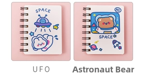 Detail view of cartoon astronaut A7 pocket coil notebooks with UFO and bear illustrations