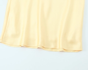 Gros plan de l'ourlet et de la texture satinée soyeuse d'une robe longue jaune
