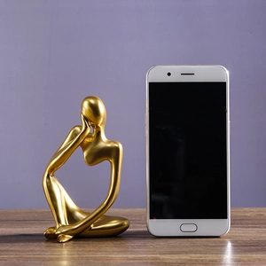 Abstract golden thinker resin sculpture with smartphone for size reference on wood desk