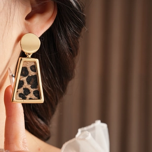 Gros plan de boucles d'oreilles trapèze léopard avec bordure dorée sur un modèle