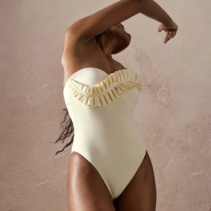 Detail of ruffled organza layer on the cream-colored off-shoulder swimsuit bodice