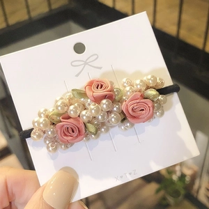Detail of Korean style hair tie with pink fabric roses, cream pearls and green leaves