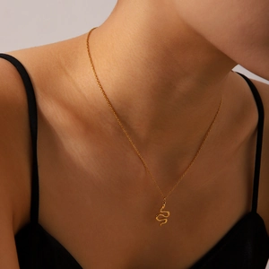 Close-up of a gold snake pendant necklace on a woman's neck, minimalist jewelry design
