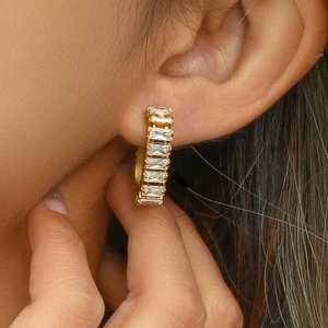 Macro view of 18K gold plated hoop earring with rectangular baguette zircons on ear