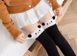 Detail of coral fleece over-knee socks featuring a cute black and white panda design