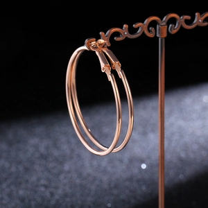 Macro shot of polished rose gold large hoop earrings on a vintage display stand