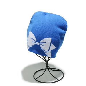 Gros plan d'un bonnet en tricot bleu vif avec motif de grand nœud blanc sur support en métal