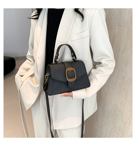 Detail of the black leather handbag featuring a vintage gold rectangular buckle and handle
