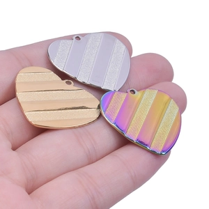 Macro view of three striped heart pendants in gold, silver and rainbow stainless steel