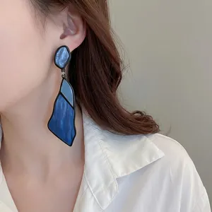 Irregular geometric blue marble acrylic drop earrings worn by a model in profile view