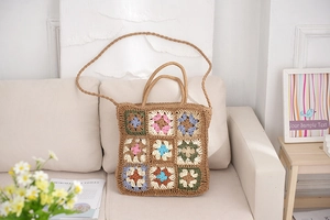 Detail of colorful granny square crochet patterns on a handmade woven straw beach tote bag