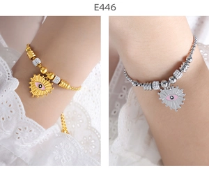 Detail of pink evil eye heart charms on gold and silver beaded snake chain bracelets
