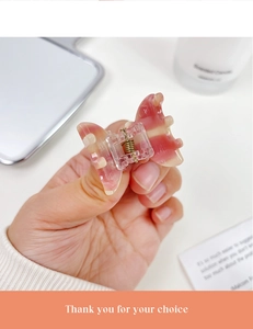Macro view of small marble pink butterfly hair claw clip held between fingers