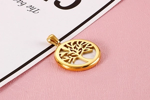 Detailed view of a gold circular Tree of Life pendant with hollow design on pink background