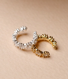 Macro detail of gold and silver ear cuffs featuring sparkling zircon gemstone inlay