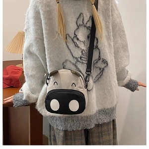 Detail view of cute black and white cow cartoon crossbody bag worn by a child model