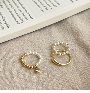 Détail de bagues dorées avec perles et zircons sur lin rustique et pages de livre ancien
