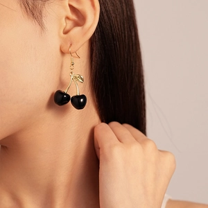Detail of dark cherry earrings with resin fruit and golden leaves on female model