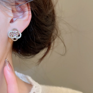 Gros plan de boucles d'oreilles trèfle bicolores avec zircons sur le mannequin