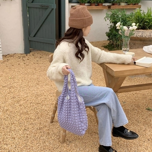 Detail of light purple puff tote bag with textured flower pattern in outdoor cafe setting
